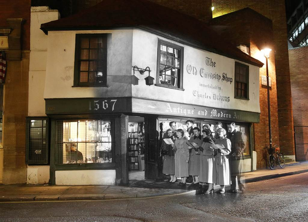 Các sinh viên hát những bài hát mừng Giáng sinh bên ngoài cửa hàng nổi tiếng Old Curiosity ở phố Portsmouth ngày 12/12/1956. Ảnh: Vintag.