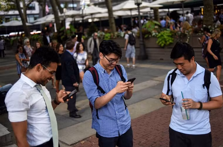 Ba bạn trẻ chăm chú theo dõi màn hình di động trong lúc đang nhập tâm chơi trò Pokemon Go ở Công viên Bryant, New York.