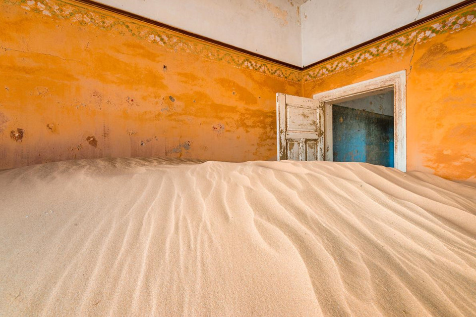 Kolmanskop, Namibia: Nằm giữa sa mạc Namib, Kolmanskop được xây dựng làm nơi ở cho công nhân của mỏ kim cương gần đó. Thị trấn bị bỏ hoang vào giữa những năm 1950, khi kim cương ở đây trở nên khan hiếm, và kể từ đó Kolmanskop dần chìm trong biển cát sa mạc. Ảnh: Alex Treadway/National Geographic.