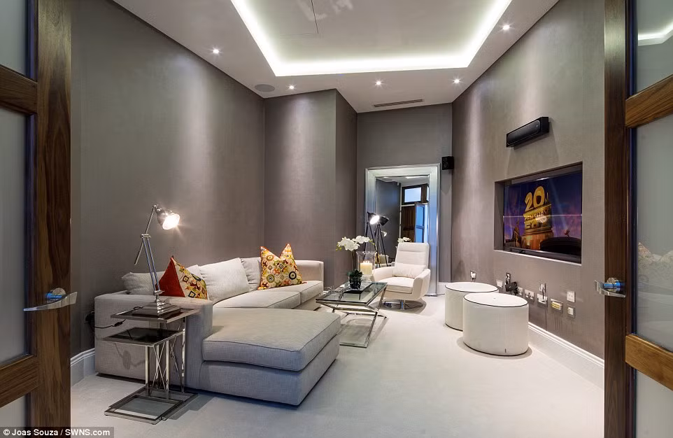 Phòng khách với sofa góc lớn, bàn uống cà phê kính, ghế bành thoải mái và hai ghế đơn.