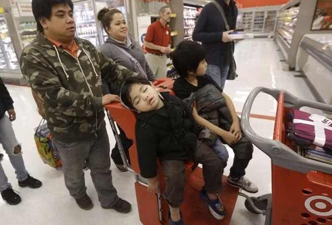 Trẻ em đi theo bố mẹ mua hàng giảm giá ngày Black Friday mệt mỏi đến ngủ gật. Ảnh: AP.