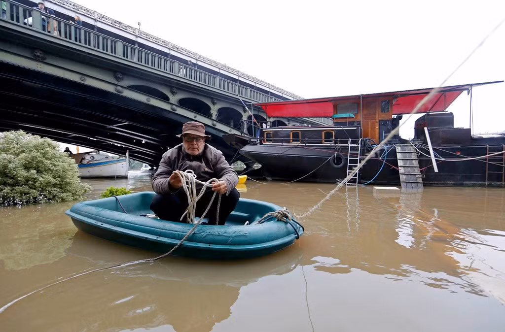 Nước tràn qua bờ kè của sông Seine ở thủ đô Paris sau 3 ngày mưa lớn, buộc người dân phải di chuyển bằng xuồng nhỏ.
