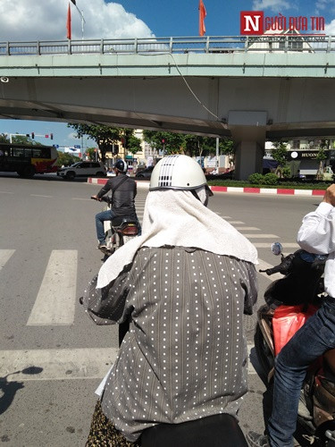 Một người phụ nữ đội cả khăn tắm lên đầu nhằm hạn chế bớt cái nắng. Dù thế, khi đứng dưới cái nắng 40 độ C, người phụ nữ vẫn không khỏi rùng mình vì quá nóng.