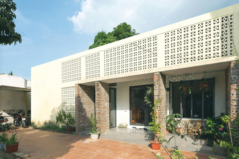 Quá trình cải tạo công trình được ghi lại bởi nhóm thiết kế. Yêu cầu của gia chủ dành cho nhóm KTS là thiết kế một công trình có không gian sống tiện nghi ngập tràn nắng gió, mà vẫn giữ lại một phần hiện trạng để tối ưu chi phí nhất có thể. Sau cải tạo, ấn tượng đầu tiên là phần mặt tiền với sự kết hợp của gạch trần mộc mạc và gạch bông gió màu trắng. Những mảng tường cũ kết hợp với tường mới không chỉ có tác dụng phân chia và tách khối, mà còn tạo ra sự đối lập một cách hài hòa giữa ngôn ngữ “cũ-mới” cho mặt đứng công trình.