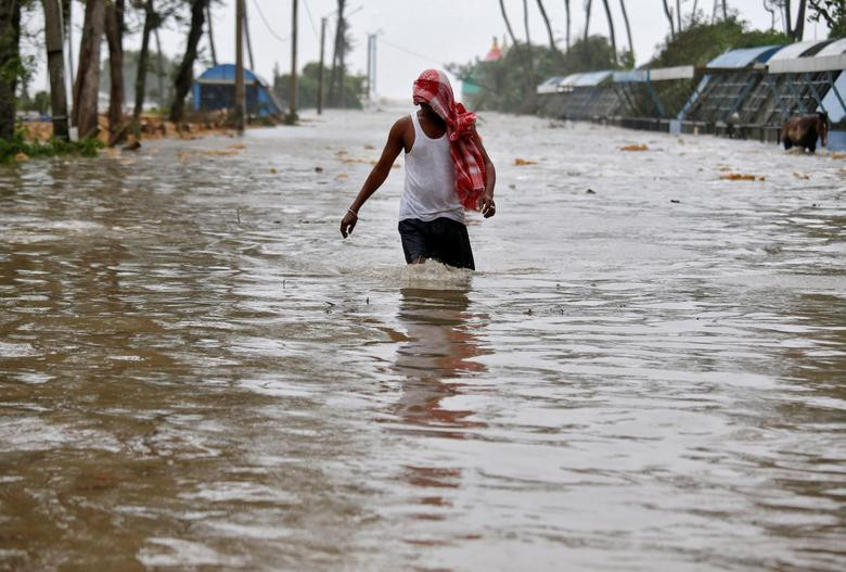 Người đàn ông đi trên con đường ngập lụt ở Digha ngày 26/5.