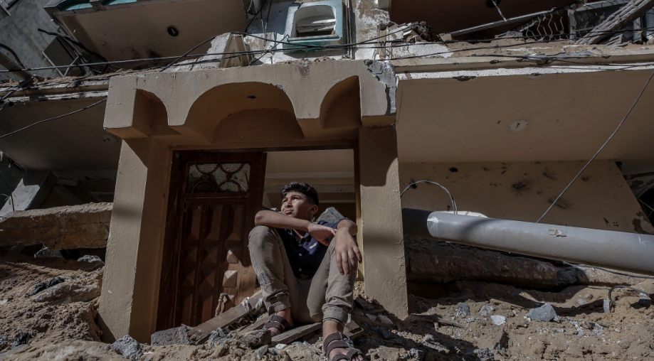Một bé trai Palestine ngồi trên đống đổ nát của ngôi nhà bị phá hủy sau đợt không kích của Israel tại thành phố Gaza.