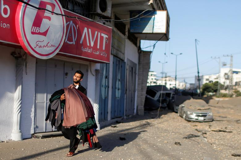 Một người đàn ông Palestine mang theo quần áo rời khỏi cửa hàng của anh tại thành phố Gaza hôm 12/5.