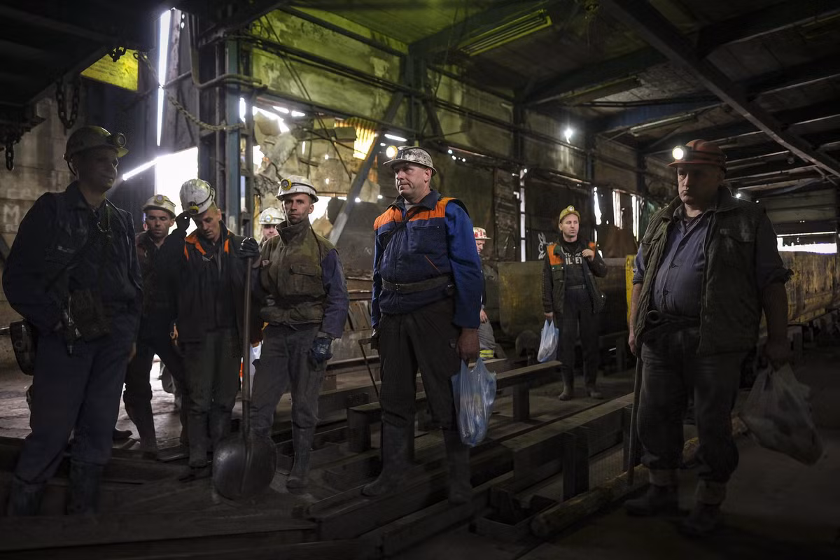 Nhóm thợ mỏ chờ thang đưa họ xuống lòng đất.