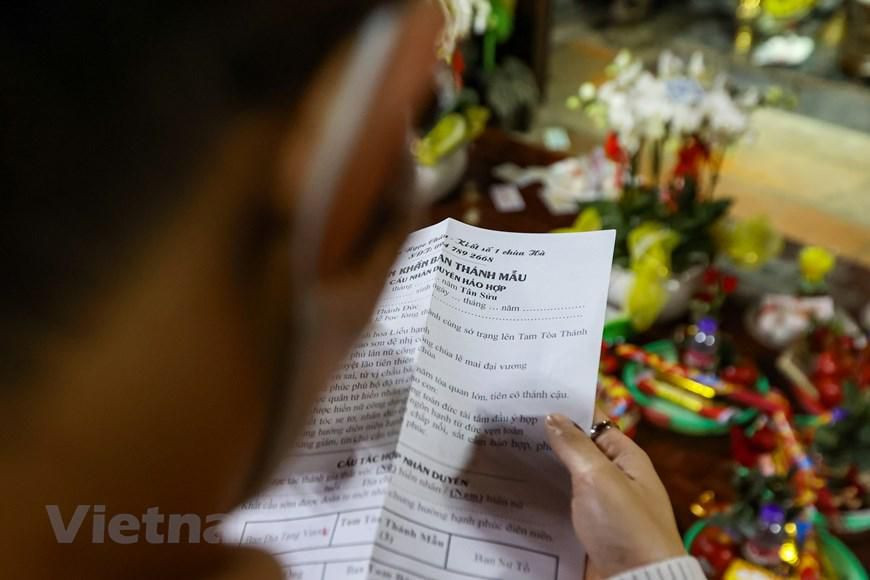 Văn khấn được thảo sẵn, mọi người chỉ cần điền tên, tuổi, địa chỉ, mong muốn tác hợp nhân duyên và khấn trước Ban Mẫu. (Ảnh: Minh Sơn/Vietnam+)
