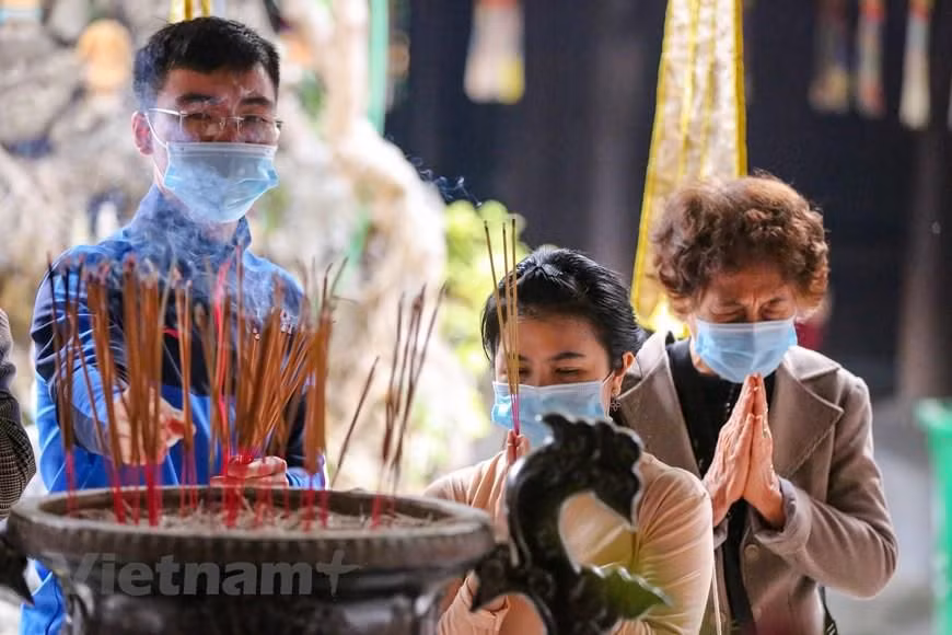Trong chiều 13/2, rất đông người dân đã đến chùa để thắp hương, cầu nguyện một năm mới bình an. (Ảnh: Minh Sơn/Vietnam+)