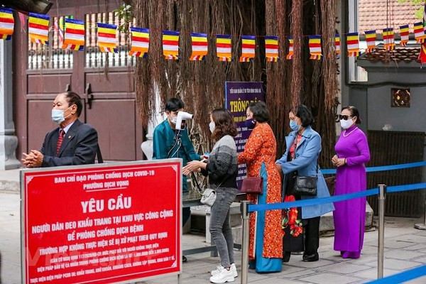 Để được vào chùa, người dân phải thực hiện nghiêm các quy định phòng tránh dịch COVID-19 như đeo khẩu trang, sát khuẩn tay và đo nhiệt độ. (Ảnh: Minh Sơn/Vietnam+)