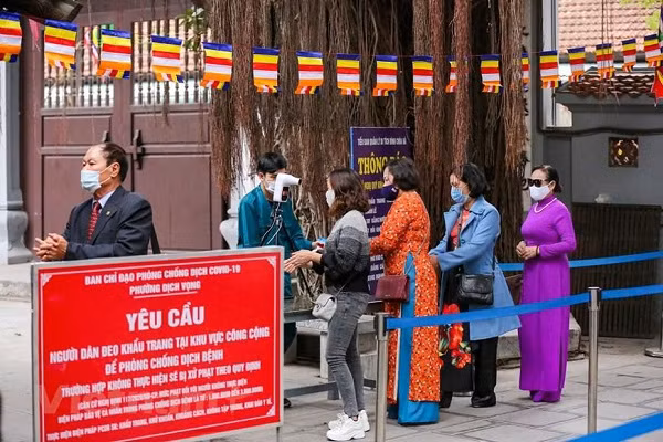 Để được vào chùa, người dân phải thực hiện nghiêm các quy định phòng tránh dịch COVID-19 như đeo khẩu trang, sát khuẩn tay và đo nhiệt độ. (Ảnh: Minh Sơn/Vietnam+)