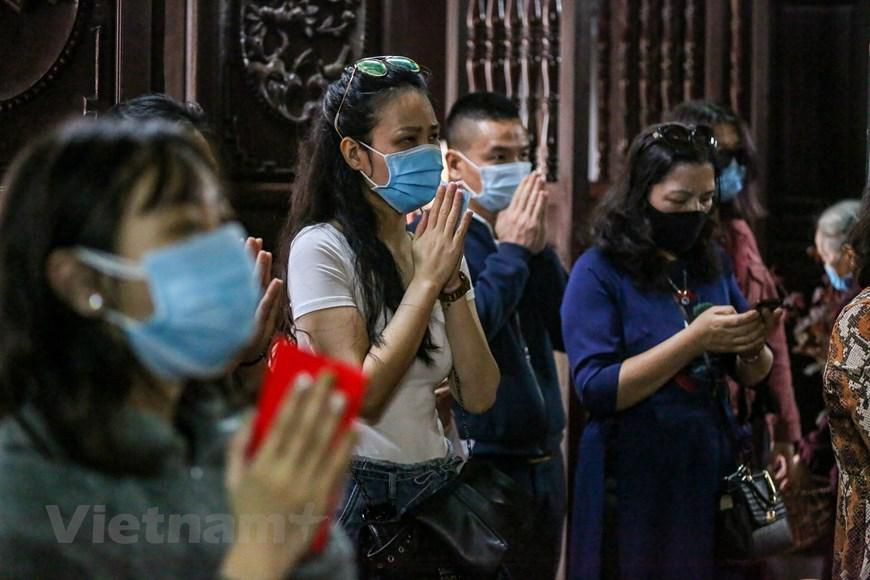 Trong lúc hành lễ, mọi người vẫn phải thực hiện nghiêm quy định đeo khẩu trang trong chùa. (Ảnh: Minh Sơn/Vietnam+)