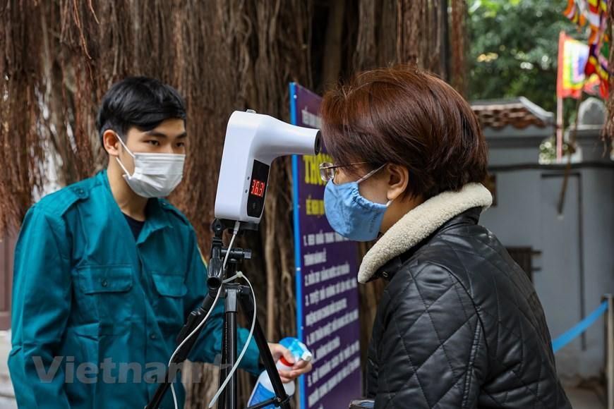 Nhà chùa đã bố trí trước cổng 2 máy đo thân nhiệt để phục vụ nhu cầu đi lễ của người dân tăng cao trong những ngày Tết. (Ảnh: Minh Sơn/Vietnam+)