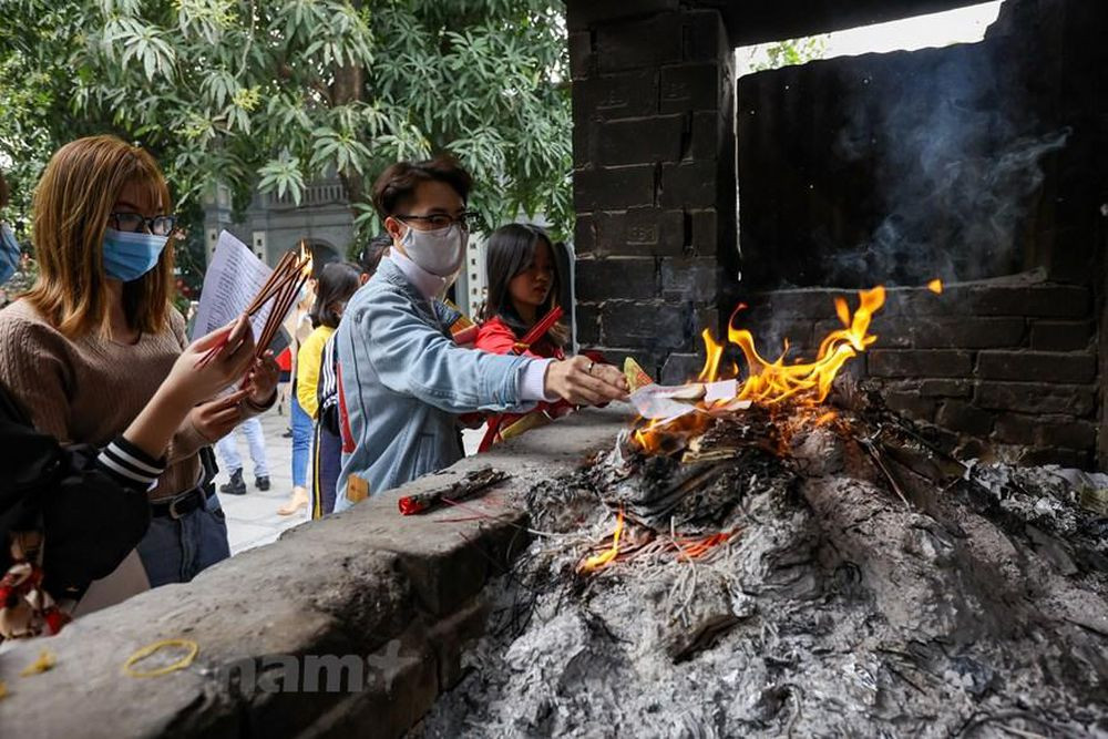 Sau khi dâng lễ xong, phải ngồi đợi 20-30 phút cho hương tàn rồi đi hạ lễ, tiền vàng và sớ sẽ được mang đi hóa. (Ảnh: Minh Sơn/Vietnam+)