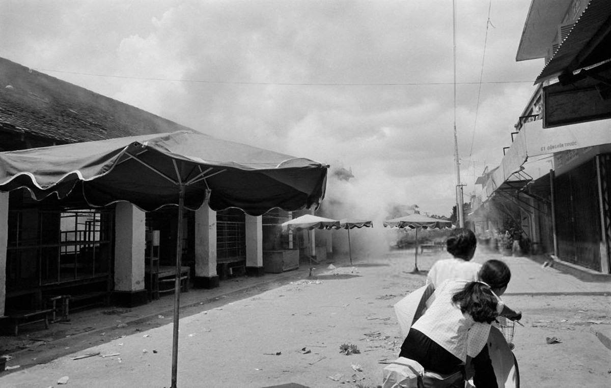 Hai người phụ nữ liều lĩnh chạy xe qua chợ Trảng Bảng khi chiến sự đang diễn ra rất gần, 25/4/1975. Ảnh: Getty.