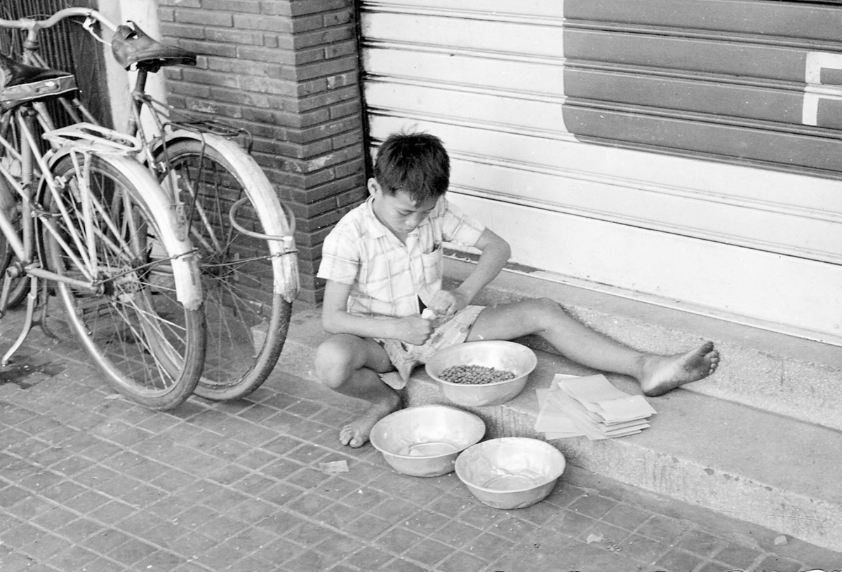 Cậu bé này chia đậu phộng rang vào những gói nhỏ để bán cho lính Mỹ trong quán bar. Ảnh: Vietnam Center and Archive.
