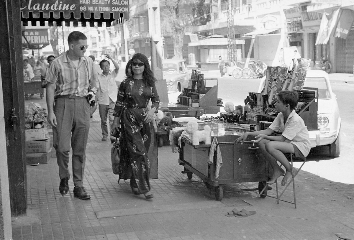 Cô gái mặc áo dài cùng một người đàn ông nước ngoài bước đi trên đường Nguyễn Văn Thinh (nay là đường Mạc Thị Bưởi), Sài Gòn năm 1966. Ảnh: Vietnam Center and Archive.