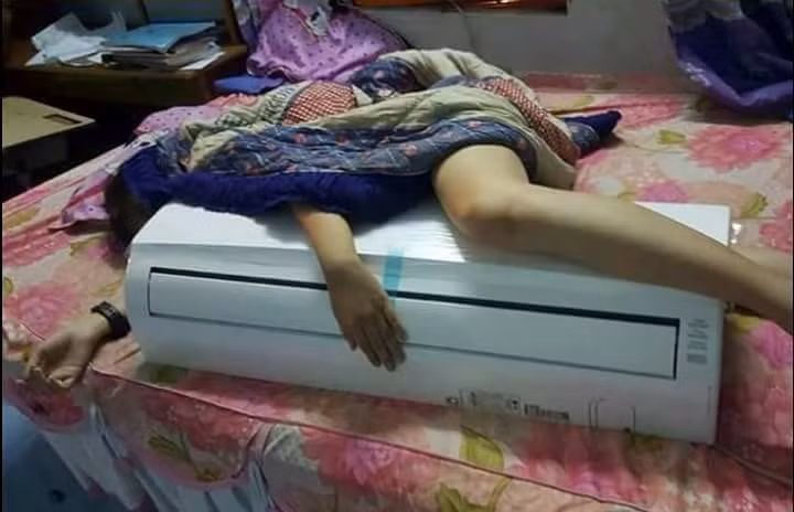 Đến khi đi ngủ cũng phải ôm chiếc điều hòa nhiệt độ. Cách chống nóng hài hước của cô gái này khiến dân mạng bật cười. Ảnh: Đỗ Xuân Định.