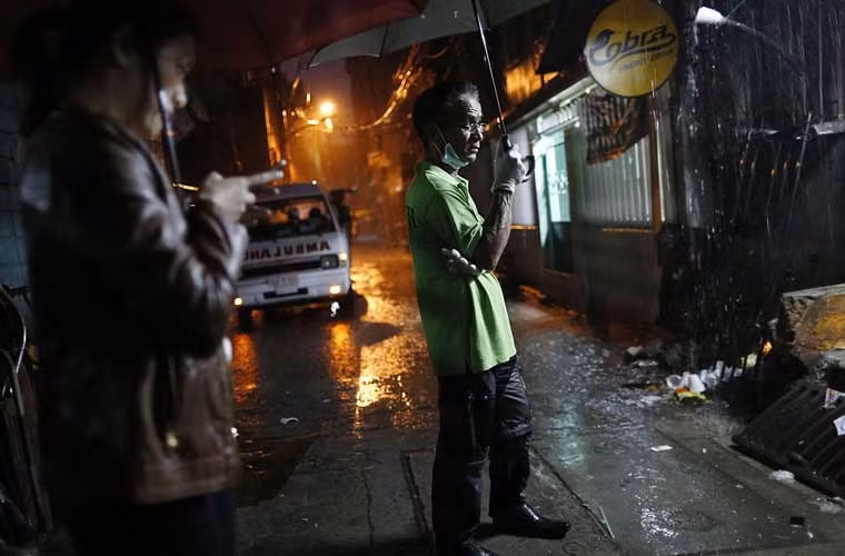 Nhân viên nhà tang lễ đứng đợi bên ngoài sau khi cảnh sát tiêu diệt một nghi phạm buôn bán ma túy.