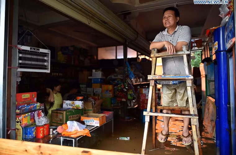 Người chủ hàng phải đứng trên bậc thang khi nước ngập gian hàng của anh ta.