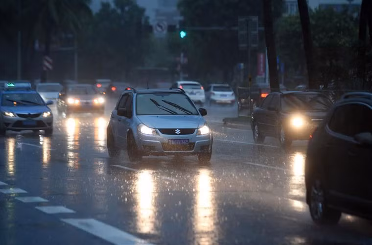 Xe ô tô di chuyển trên đường trong lúc trời mưa khá to ở Hải Khẩu tối 18/8.