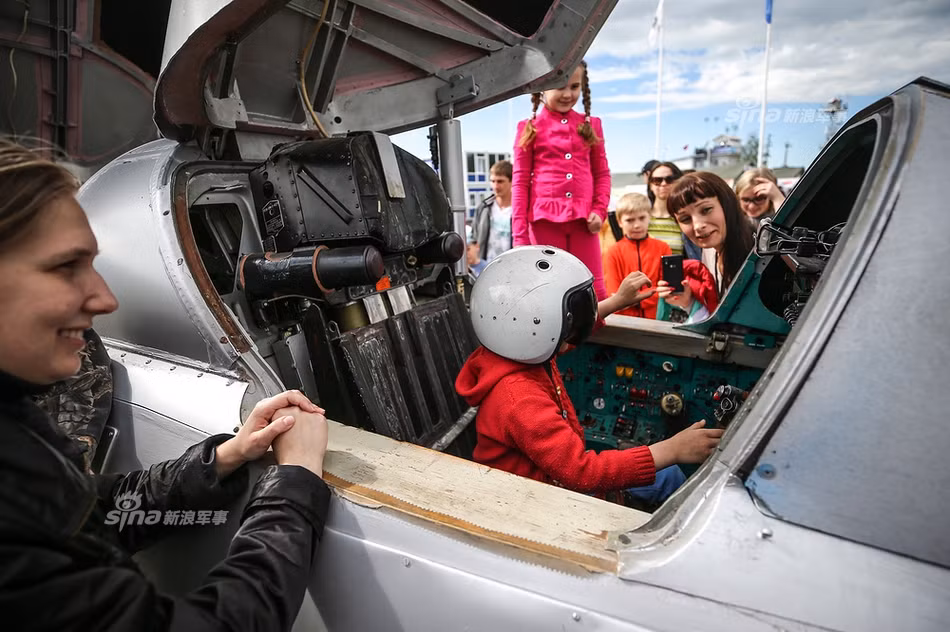 Rất nhiều em nhỏ được cha mẹ đưa tới triển lãm đã tỏ ra cực kỳ thích thú khi được tận tay sờ vào những cỗ máy tuyệt tác cơ khí trị giá hàng chục triệu USD này. Ảnh: Một bé gái được ngồi hẳn vào trong buồng lái của chiếc tiêm kích, bên ngoài còn rất nhiều bạn nhỏ xếp hàng chờ đến lượt mình được ngồi thử vào vị trí phi công. Nguồn ảnh: Sina.