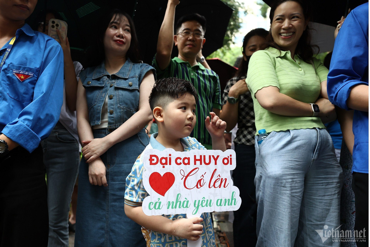 Cả gia đình đi từ quận Hoàng Mai, đứng chờ thí sinh Trương Công Gia Huy (lớp 9A4, Trường THCS Hoàng Mai) tại điểm thi THPT Trần Phú trong mưa. Em trai của sĩ tử sung sướng ôm lấy anh trong tiếng reo hò của những người xung quanh.