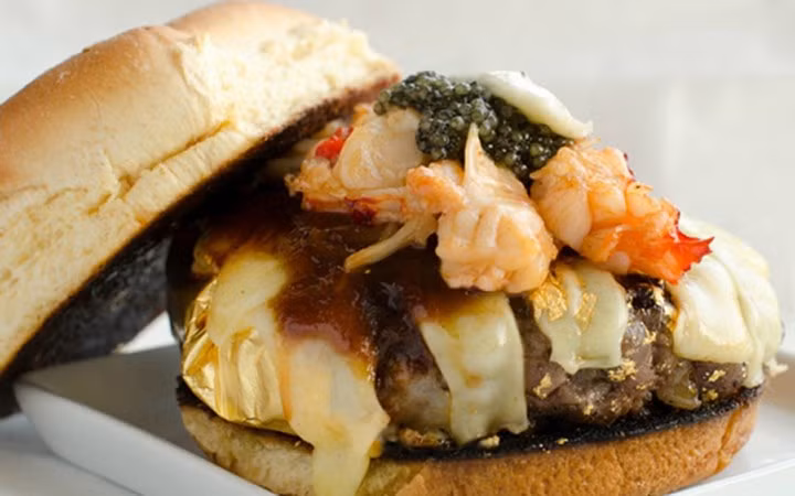 Cửa hàng bán đồ ăn nhanh 666 Burger, New York, Mỹ đã tạo ra một cơn sốt khi bán chiếc bánh Douche Burger với giá 666 USD. Nguyên liệu để làm bánh gồm phô mai hảo hạng, sốt BBQ, muối đá từ dãy Himalaya, trứng cá muối, gan ngỗng, tôm hùm, nấm truffle và những mảnh vàng lấp lánh được trộn cùng thịt bò Kobe. (Ảnh: KT)
