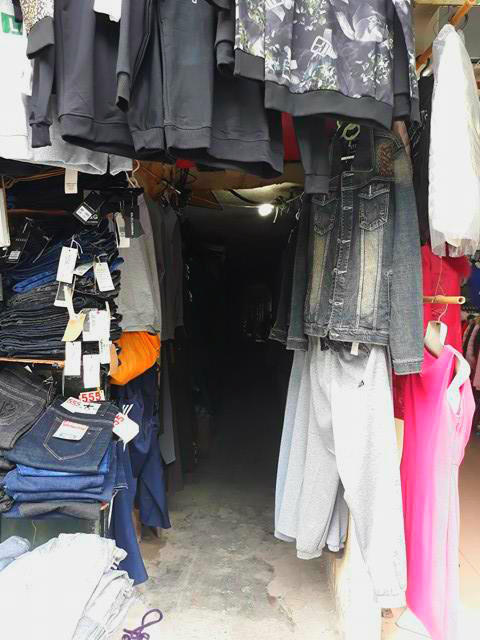 Quần áo được treo đầy cửa ngõ ra vào để tận dụng diện tích trưng bày gian hàng. Đây là con ngõ chỉ dành cho một xe máy, nếu hai xe máy đi ngược chiều thì tránh nhau khá vất vả.