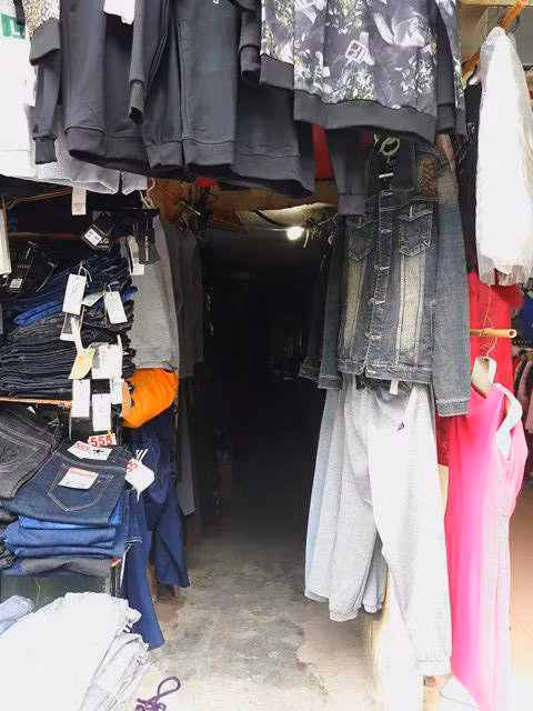 Quần áo được treo đầy cửa ngõ ra vào để tận dụng diện tích trưng bày gian hàng. Đây là con ngõ chỉ dành cho một xe máy, nếu hai xe máy đi ngược chiều thì tránh nhau khá vất vả.