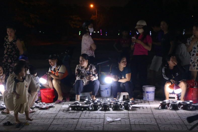 Chợ không có lều bạt, hàng quán, bàn ghế, mỗi người chọn một khoảng vỉa hè để bày mực ra bán. Trên tay mỗi người bán là một chiếc đèn điện, vừa dùng để soi sáng cho khách chọn mực, vừa tạo hiệu ứng để những con mực lấp lánh hơn. (Ảnh: Gia đình và Xã hội).