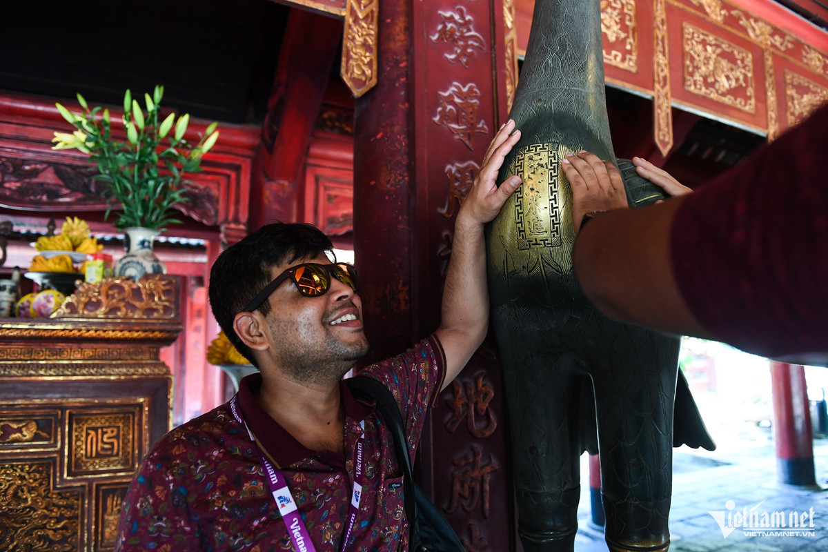 Sau khi được hướng vẫn viên giải thích về các hiện vật trong Văn Miếu - Quốc Tử Giám, một du khách đã thử sờ lên bức tượng hạc để cầu may.