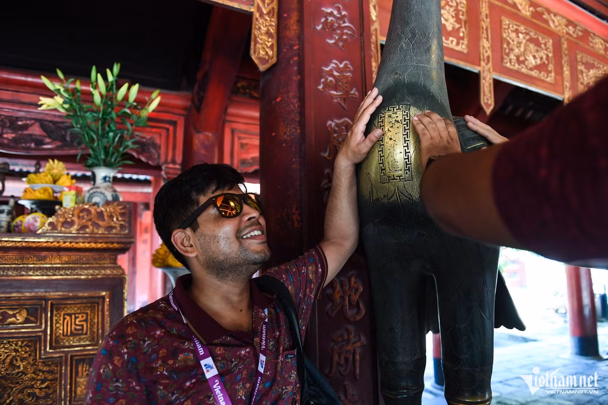 Sau khi được hướng vẫn viên giải thích về các hiện vật trong Văn Miếu - Quốc Tử Giám, một du khách đã thử sờ lên bức tượng hạc để cầu may.