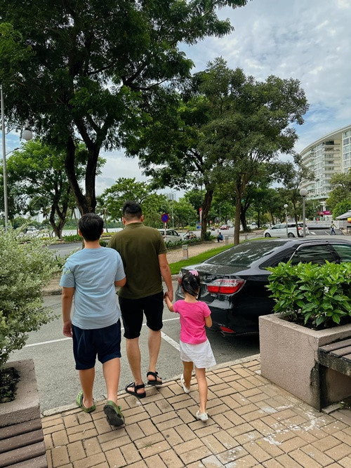 Chồng trẻ của Lê Phương nắm tay hai con cùng bước qua đường.