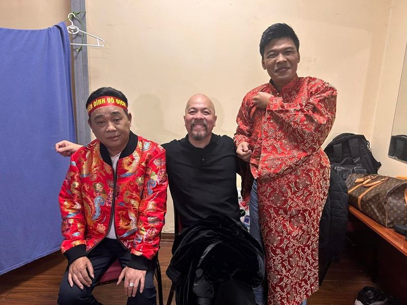 NTK Đức Hùng thiết kế trang phục cho các nghệ sĩ tham gia Táo quân 2025. Mới đây, anh chia sẻ loạt ảnh hậu trường ghi hình chương trình ngày đầu tiên (ngày 15/1). Trong ảnh, nghệ sĩ Quốc Khánh (ngoài cùng bên trái) mặc áo tông màu đỏ, đeo băng rôn in chữ "Thiên đình vô địch". Nhiều khán giả cho rằng Quốc Khánh vẫn đóng vai Ngọc Hoàng trong Táo quân 2025. Ảnh: FB Đức Hùng.