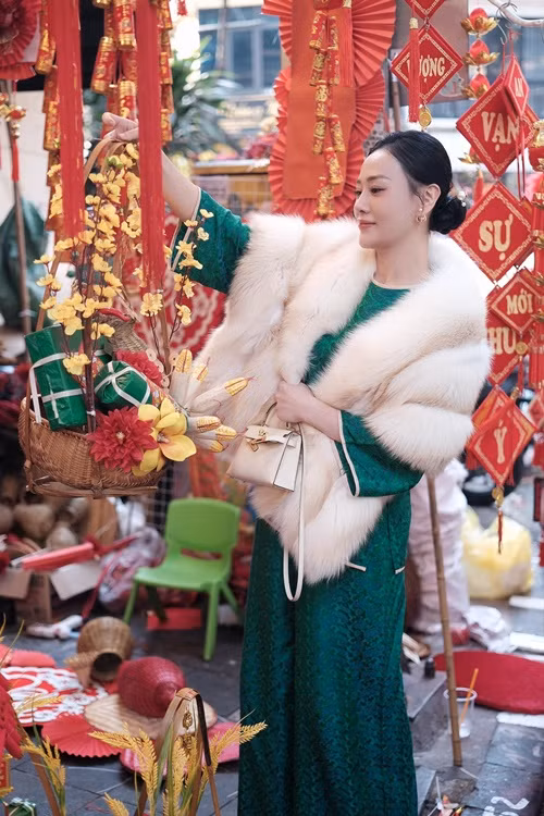 Nữ diễn viên lựa chọn đồ trang trí Tết trên phố Hàng Mã. Phương Oanh cho biết, cô đã mua hai chú lợn đất để hai con đựng tiền tiết kiệm. Ảnh: FB Phương Oanh.
