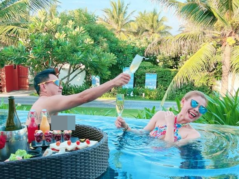 Hình ảnh vợ chồng giọng ca Búp bê vui đùa trong bể bơi trong một chuyến nghỉ dưỡng. Ảnh: FB Thanh Thảo.