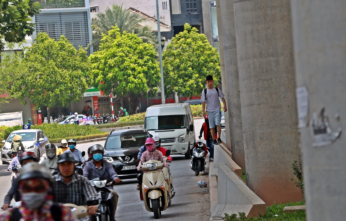 Trên đường Cầu Giấy, một thanh niên đi bộ dưới chân đường sắt Nhổn - ga Hà Nội, phía ngoài trời nắng như đổ lửa.