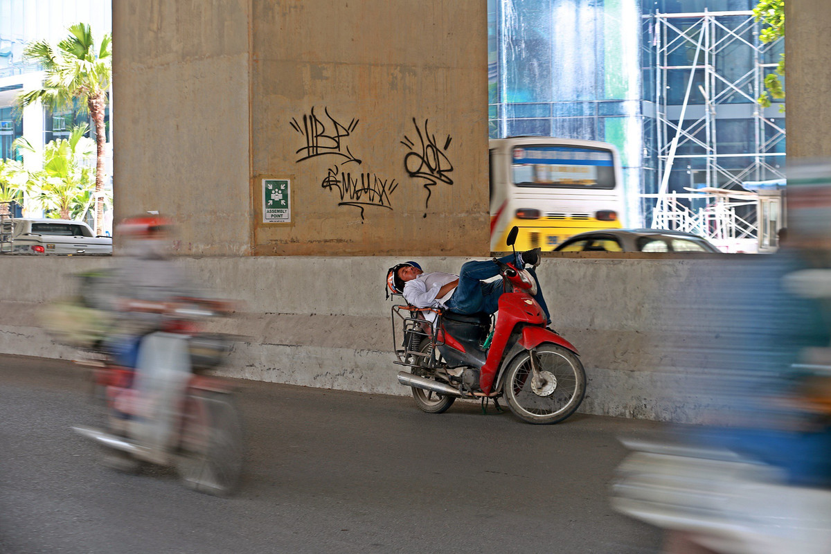 Người đàn ông dựng xe máy tranh thủ chợp mắt giữa trưa nắng trên đường Cầu Giấy.