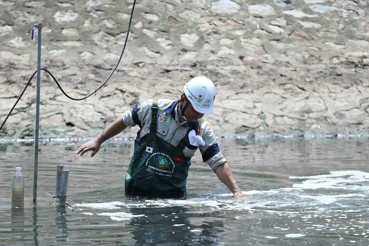 TS Kubo Jun - chuyên gia Nhật Bản (Cố vấn kỹ thuật Tổ chức xúc tiến thương mại - môi trường Nhật Bản, Chuyên gia công nghệ máy sục khí công nghệ nano JVE) bước xuống dòng nước đen xì của sông Tô Lịch (Hà Nội) kiểm tra máy nano lọc nước.