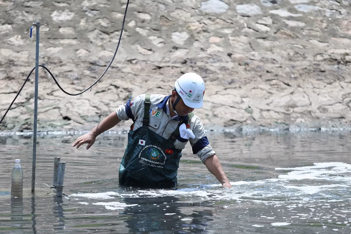 TS Kubo Jun - chuyên gia Nhật Bản (Cố vấn kỹ thuật Tổ chức xúc tiến thương mại - môi trường Nhật Bản, Chuyên gia công nghệ máy sục khí công nghệ nano JVE) bước xuống dòng nước đen xì của sông Tô Lịch (Hà Nội) kiểm tra máy nano lọc nước.
