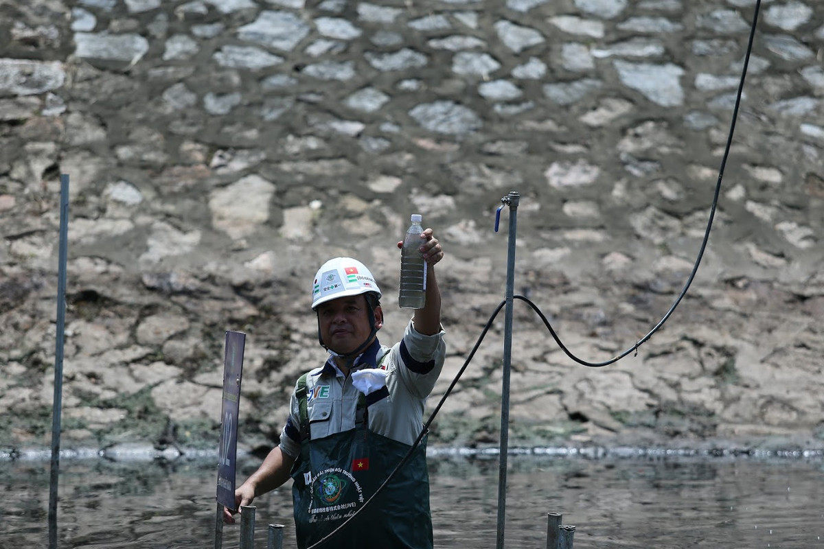 TS Kubo Jun giơ chai nước được lấy tại vị trí đặt máy trên sông Tô Lịch.