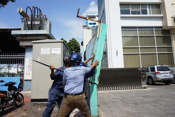 Lực lượng công ích đang xô đổ bức tường nhiều vết nứt, cao 3 mét, chiếm vỉa hè trước tòa nhà cơ quan đại diện Bộ Công thương tại TP HCM. Ông Hải nói: "Nếu quận không đến xử lý và bức tường đổ đè chết người thì ai chịu trách nhiệm?".