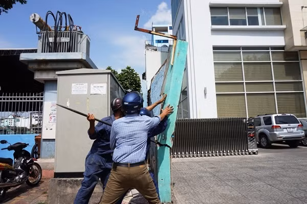 Lực lượng công ích đang xô đổ bức tường nhiều vết nứt, cao 3 mét, chiếm vỉa hè trước tòa nhà cơ quan đại diện Bộ Công thương tại TP HCM. Ông Hải nói: "Nếu quận không đến xử lý và bức tường đổ đè chết người thì ai chịu trách nhiệm?".