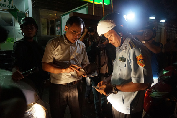 Tài xế một xe biển đỏ đang trình giấy tờ cho tổ công tác.