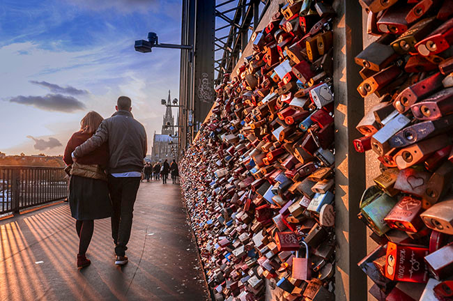 Một cặp tình nhân dìu nhau đi dạo trên cây cầu tình yêu Hohenzollern, thành phố Koln