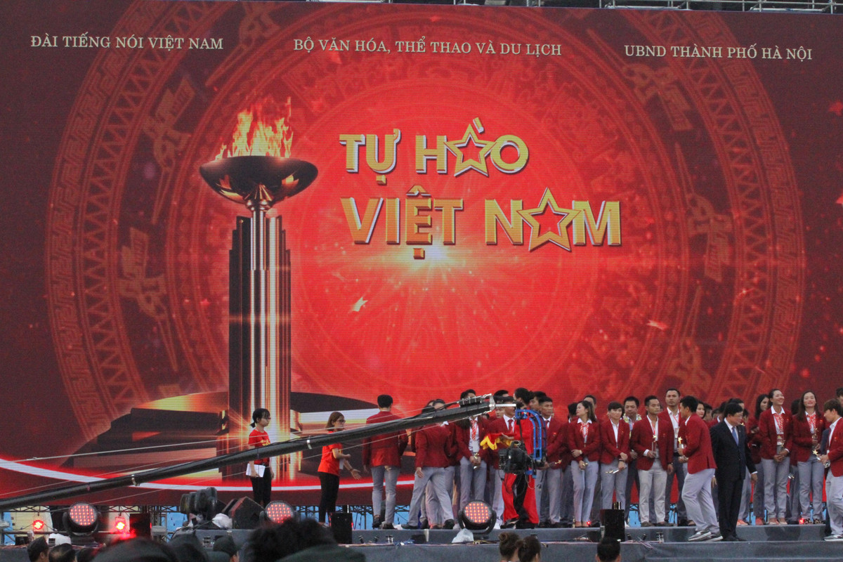 Đoàn đội tuyển thể thao trên sân khấu lễ vinh danh, những lá cờ tổ quốc rợp sân Mỹ Đình, cổ động viên hào hứng mừng thành tích của toàn đoàn thể thao