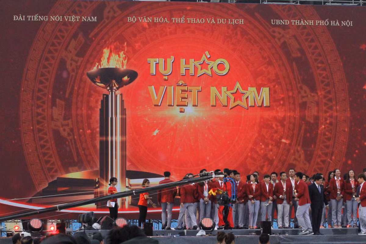 Đoàn đội tuyển thể thao trên sân khấu lễ vinh danh, những lá cờ tổ quốc rợp sân Mỹ Đình, cổ động viên hào hứng mừng thành tích của toàn đoàn thể thao