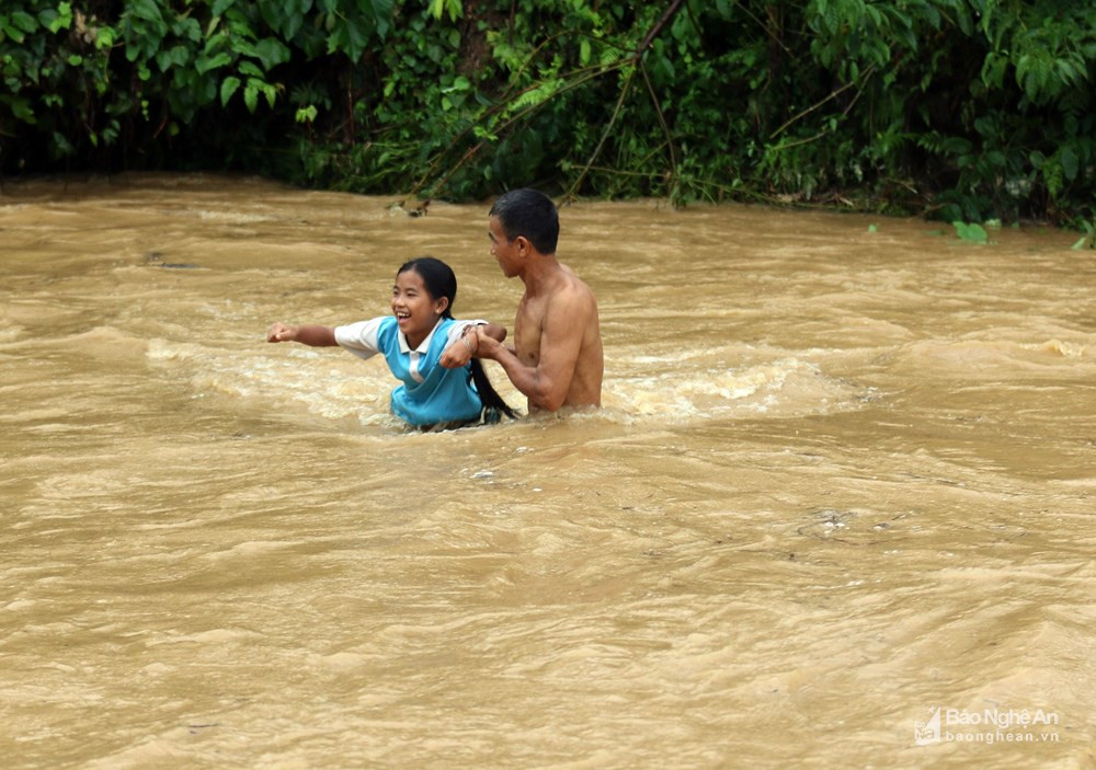 Một người đàn ông giúp con gái vượt lũ về nhà. Ảnh: Đào Thọ